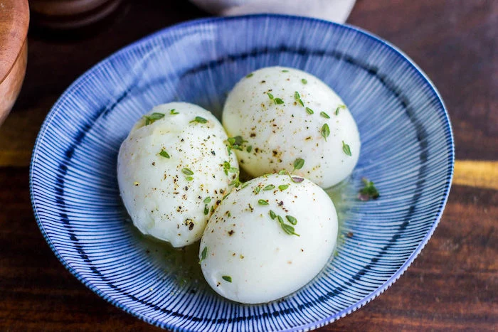 three boiled eggs, with thyme and butter, easy keto meals, blue and white bowl, wooden table
