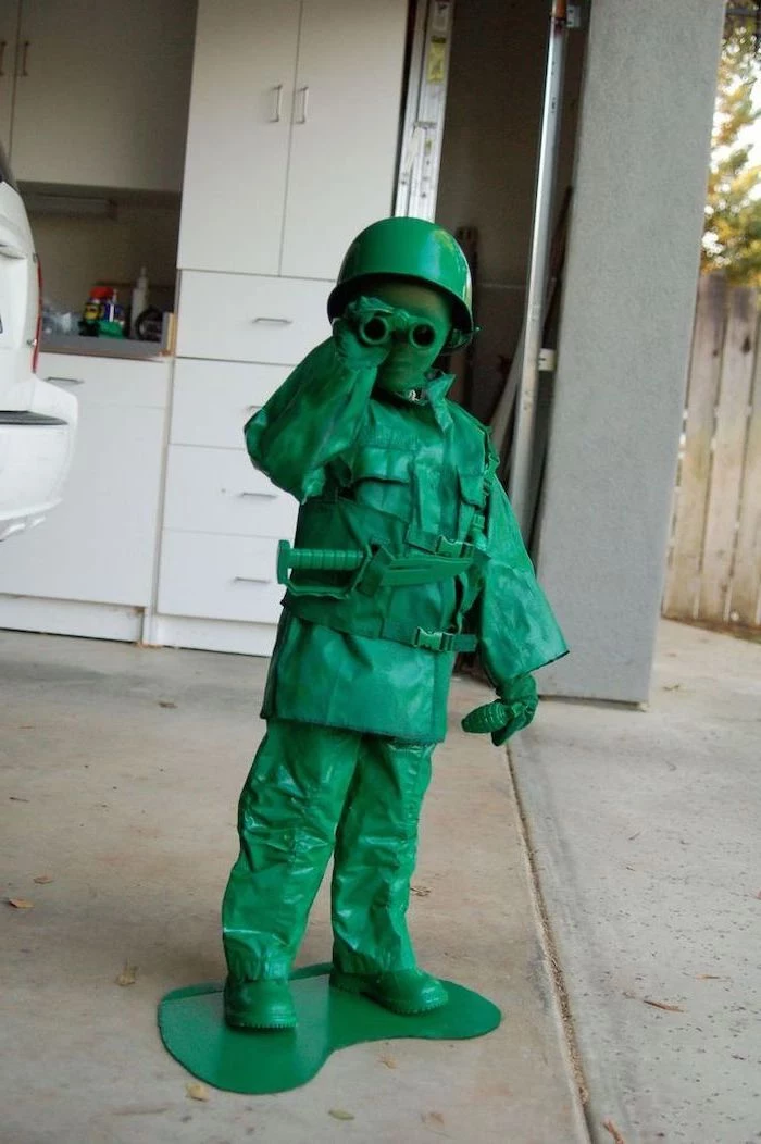 little boy, dressed as a toy soldier, halloween costumes for kids, all green costume, white cupboards, in the background