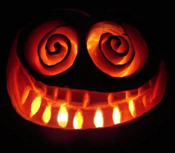 black background, jack o lantern designs, face carved into a pumpkin, lit by candles