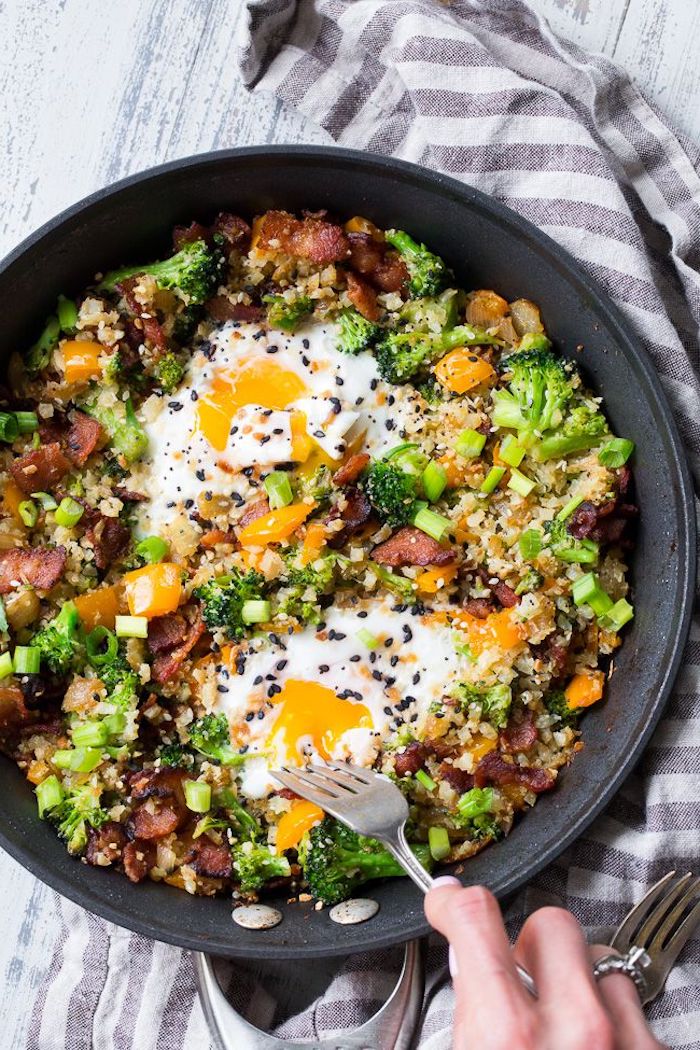 cauliflower rice, with eggs and bacon, best keto recipes, chives and peppers on top, black frying pan