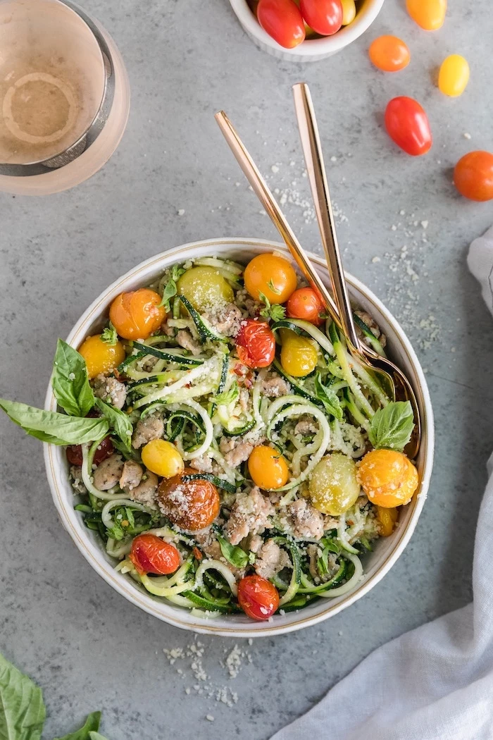 cherry tomatoes, zucchini spaghetti recipe, chicken fillet, basil leaves, in a white bowl, granite countertop