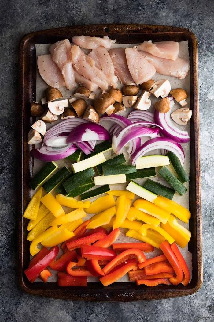 chicken fillet, mushrooms and onion, zucchini and peppers, arranged on a pan, healthy meal prep