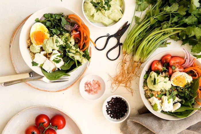 spinach salad, with guacamole, boiled eggs, healthy meal prep recipes, cherry tomatoes, white plates