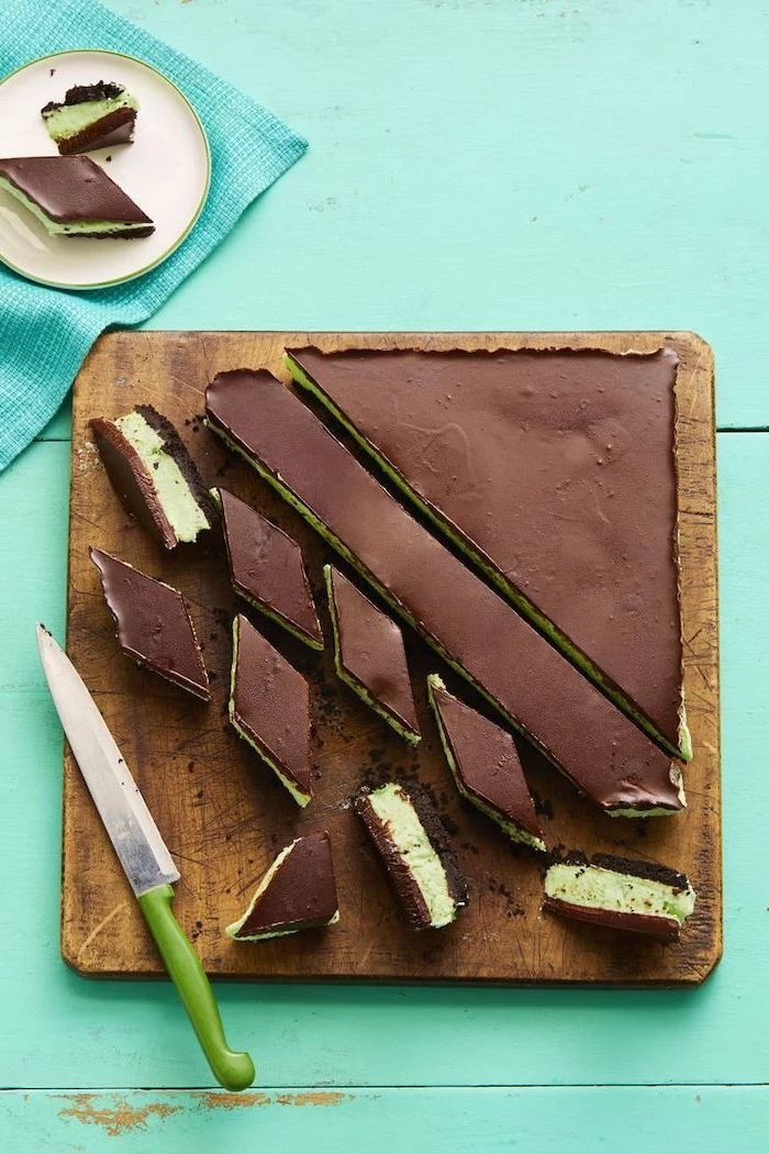 chocolate cake, mint mousse, cut into pieces, no bake desserts, on a wooden cutting board, turquoise wooden table