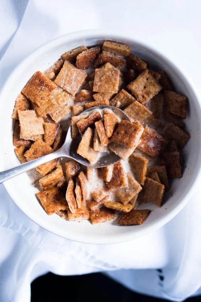 cinnamon toast crunch, soaked in milk, in a white bowl, with silver spoon, keto breakfast ideas, white table cloth