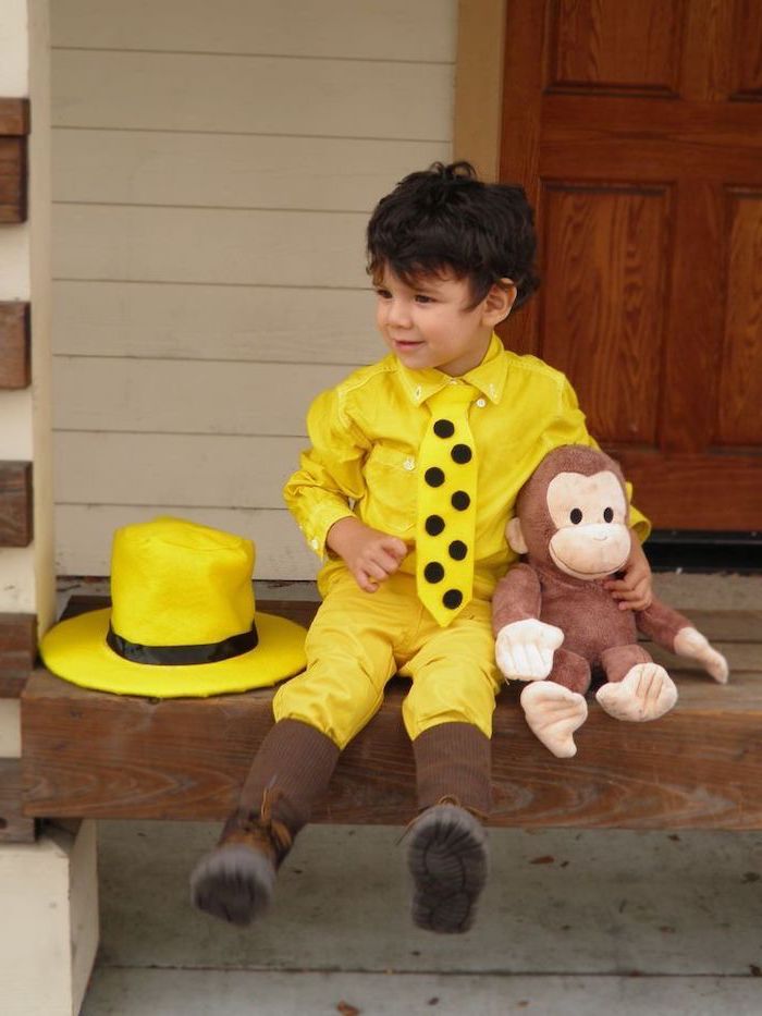 little boy, sitting on a step, dressed as the man in the yellow hat, carrying curious george, plush toy, halloween costumes for kids