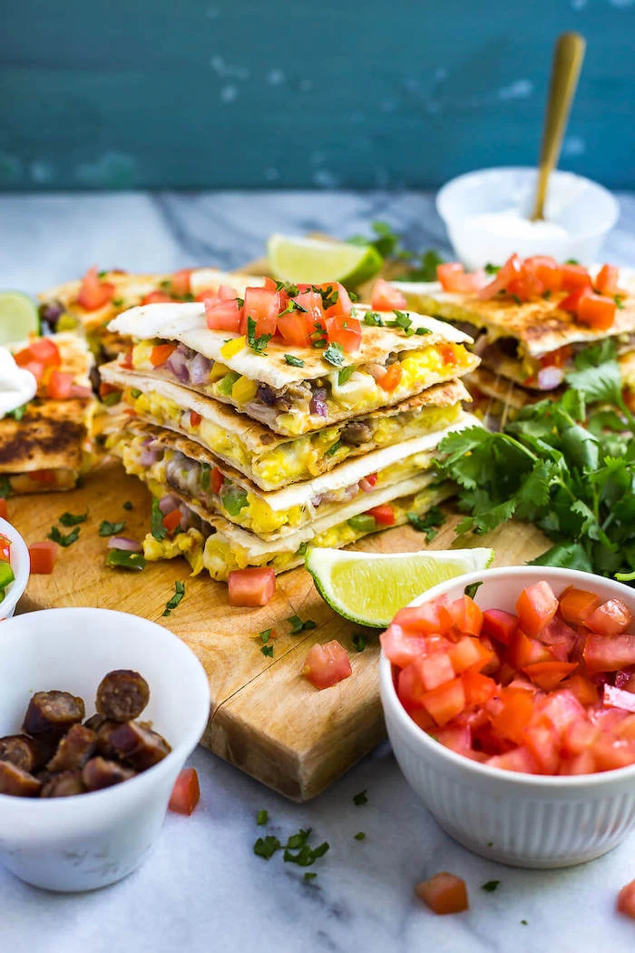 meal prep ideas, breakfast quesadillas, chopped tomatoes and sausages, in white bowls, wooden cutting board