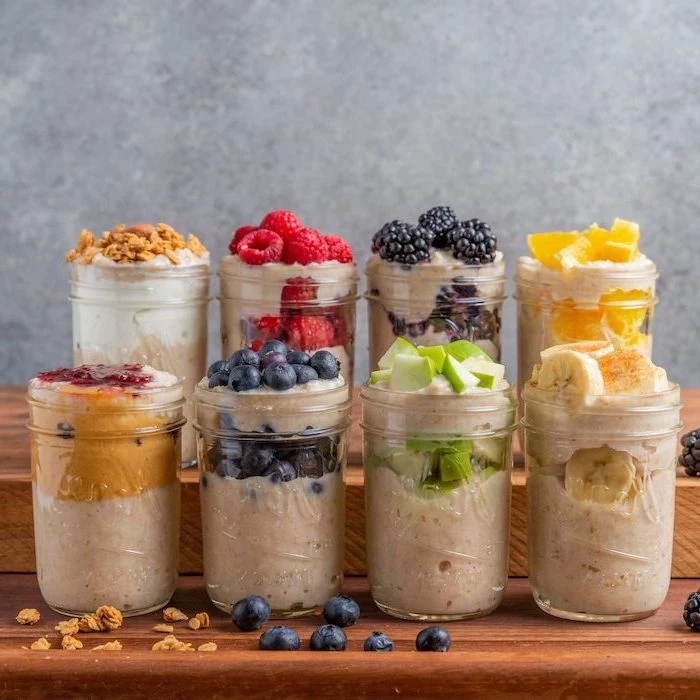 mason jars, filled with oatmeal and yoghurt, easy healthy lunch ideas, different fruits on top, berries and bananas, nuts and apples