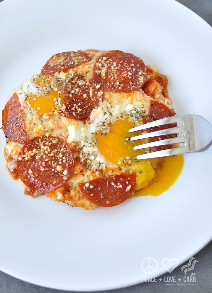 keto diet breakfast, egg pizza, with pepperoni slices, on white plate, silver fork, granite countertop