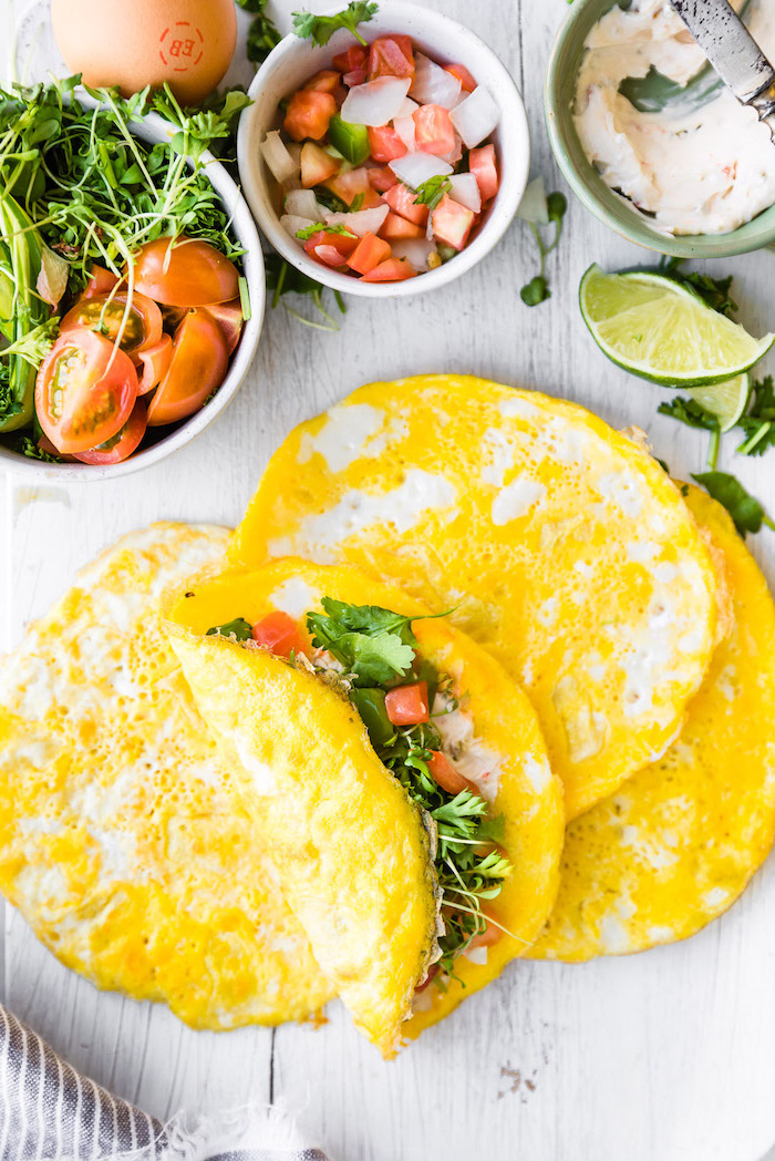 healthy lunches for work, egg wraps, chopped tomatoes and onion, parsley inside, white wooden table