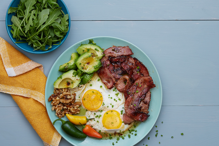 bacon and eggs, peppers and avocado, walnuts and chives, on blue plate, low carb breakfast recipes, blue wooden table