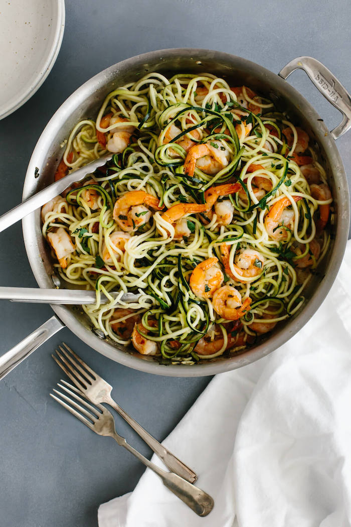 zoodles with shrimp, in a skillet, zucchini noodles spaghetti, silver tongs, silver forks, white cloth