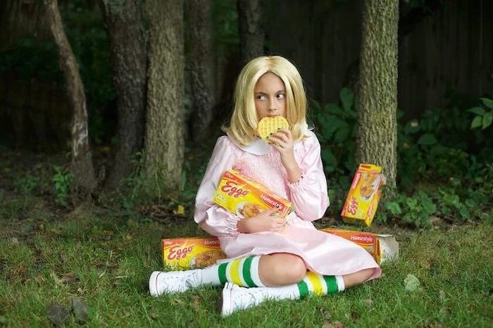 girl dressed as eleve, from stranger things, eating eggos, cute halloween costumes for girls, boxes of eggo waffles