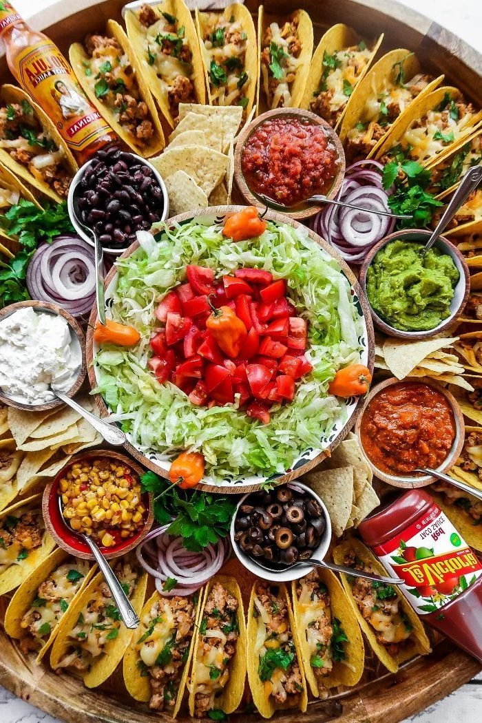 ground beef taco recipe, glass bowls, filled with different ingredients, mini tacos, arranged on a large, wooden tray
