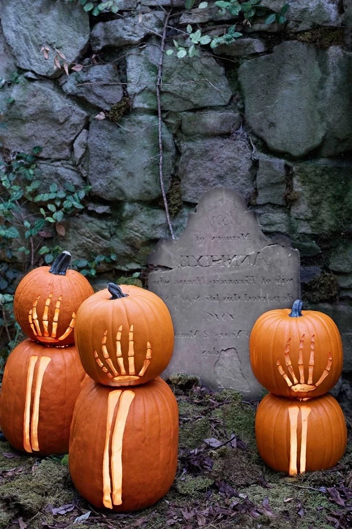 pumpkin carving, grave tombstone, large rocks, pumpkins with skeleton hands, carved into them