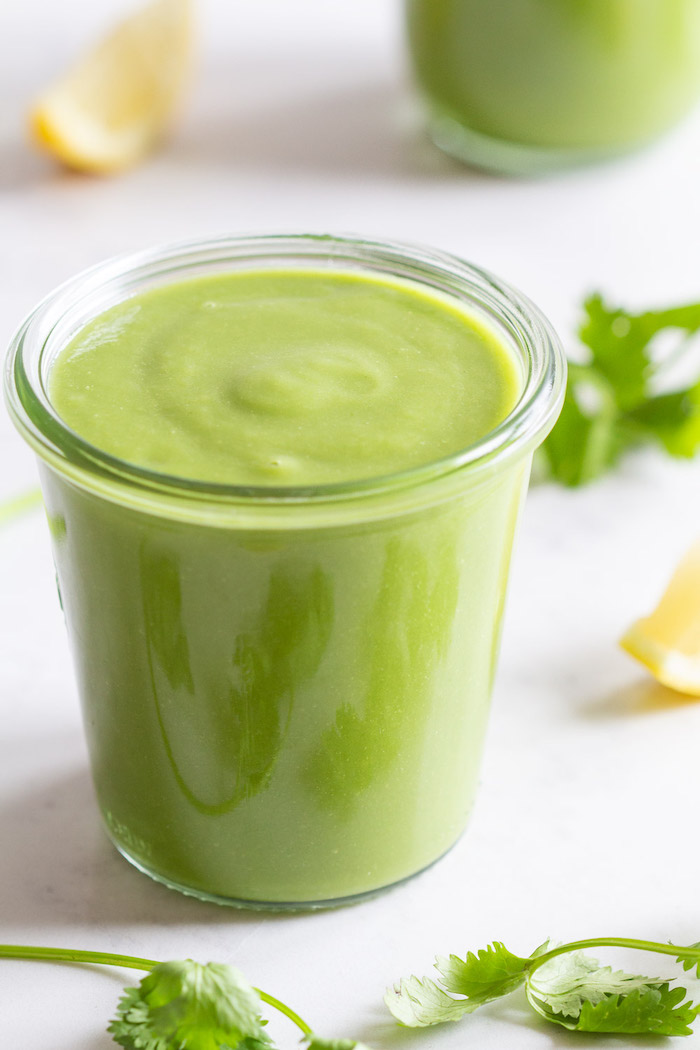 keto breakfast, green smoothie, in a small glass, lemon slices and parsley, scattered around, white table