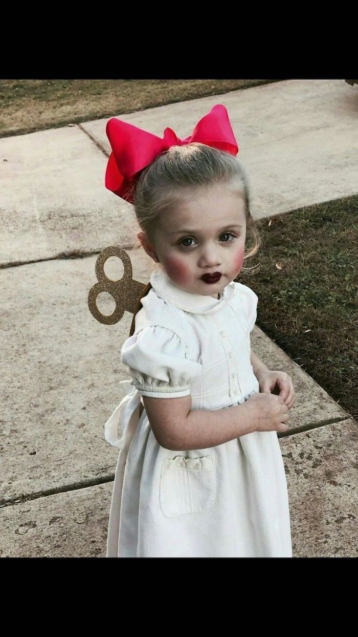 little girl, with blonde hair, dressed as a doll, wearing white dress, red bow, halloween costume ideas for girls