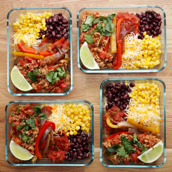 meal prep for the week, four glass containers, filled with corn and cheese, peppers and meat, black beans