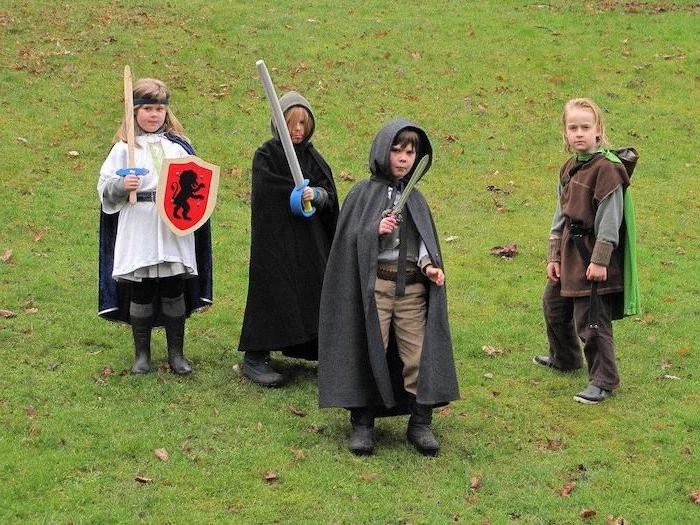 four boys, dressed as hobbits, halloween costume ideas for girls, hobbit inspired, standing on a grass field