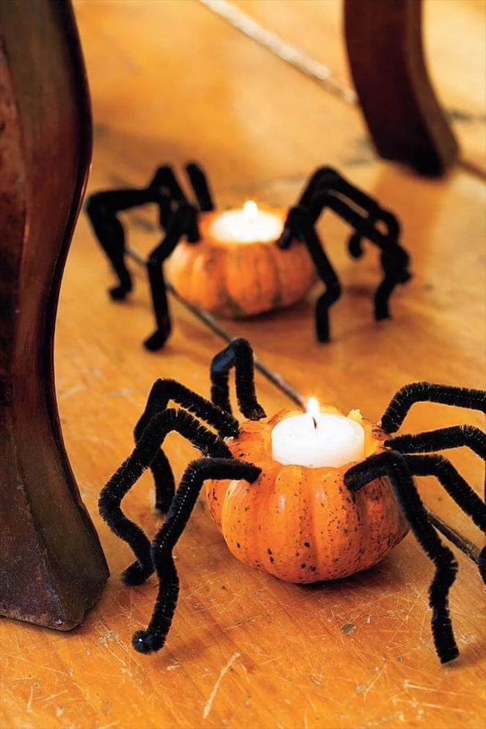 two small pumpkins, with candles inside, spider legs, glued to them, pumpkin faces ideas, wooden floor