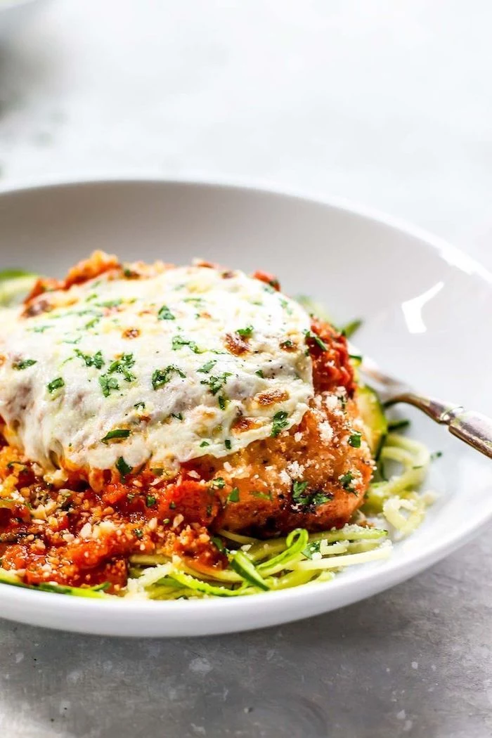 zucchini noodles recipe, chicken parmesan, tomato sauce, in a white plate, granite countertop