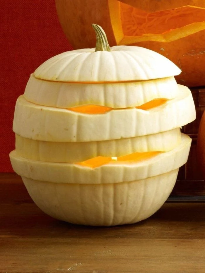 white pumpkin, carved and sliced, in the shape of a mummy, cute pumpkin carvings, wooden table