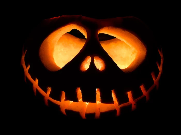 jack skellington, carved into a pumpkin, lit by candle, easy pumpkin carving, black background