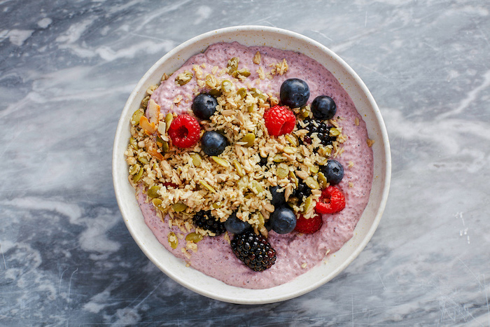 berry pudding, with chia seeds and granola, blueberries and raspberries, keto breakfast no eggs, white bowl