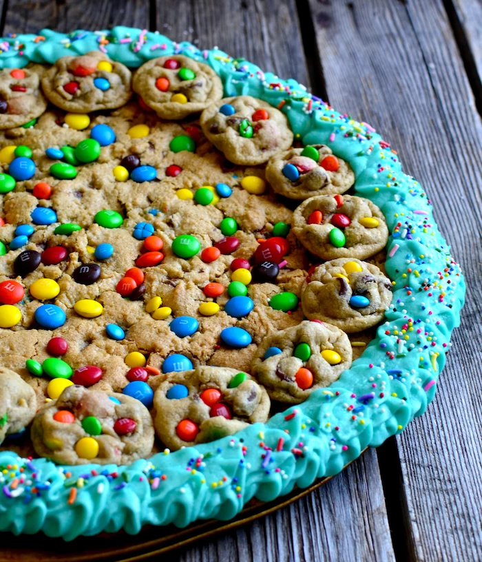 cookie dough cake, with smaller cookies, with m and ms, blue frosting around, how to make homemade cookies, wooden table
