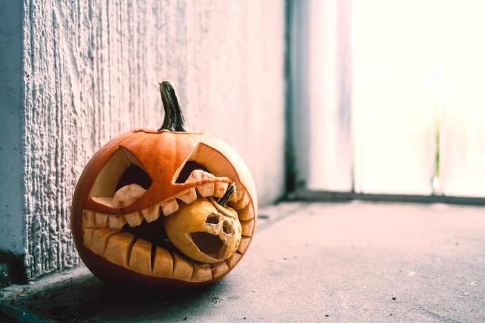 large pumpkin, eating a small pumpkin, pumpkin carving faces, cement floor, white wall