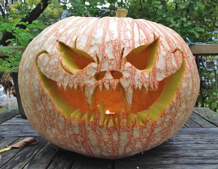 scary face, carved into a pumpkin, lit by a candle, easy pumpkin carving, wooden table, trees in the background