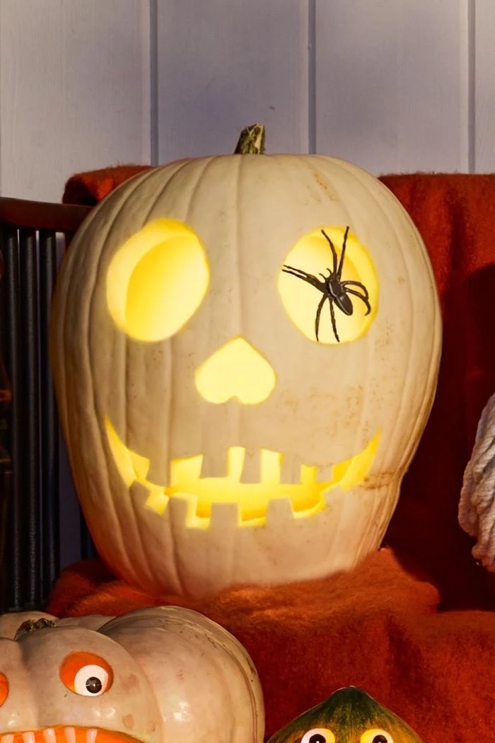 white pumpkin, pumpkin carving faces, plastic spider, inside the eye, pumpkin carving faces, orange blanket