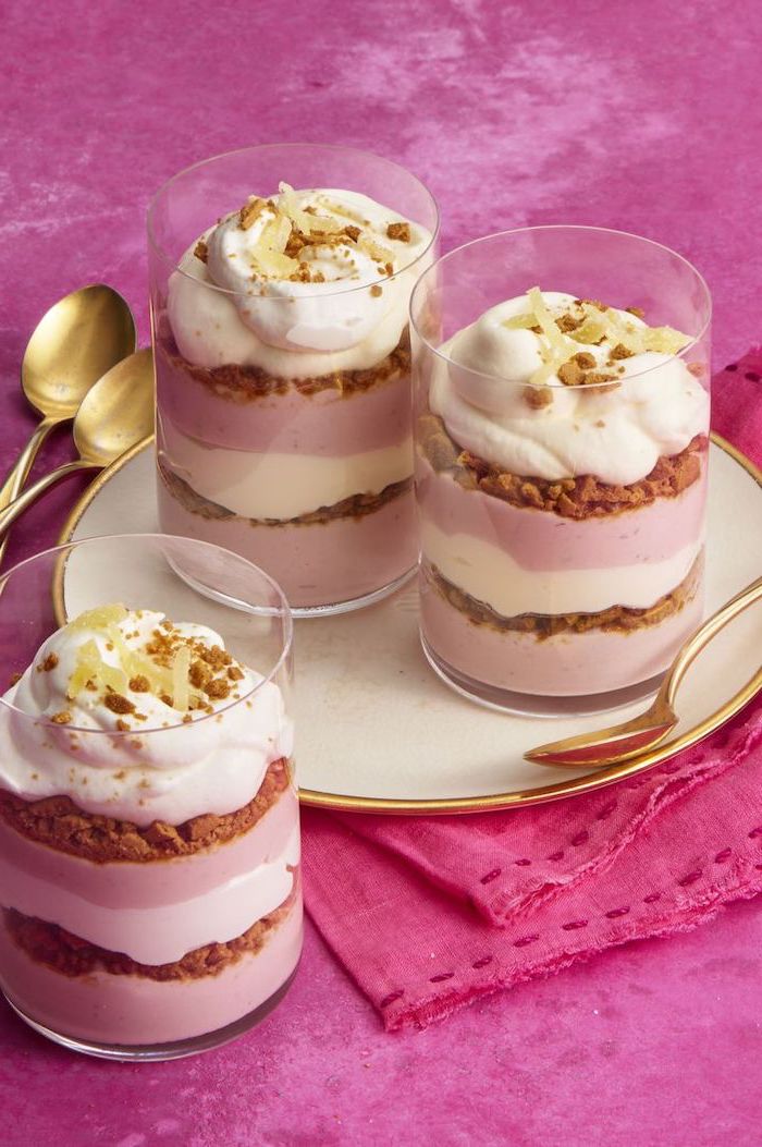 layered cheesecake, in glasses, on a white plate, no bake desserts, pink background, brass spoons