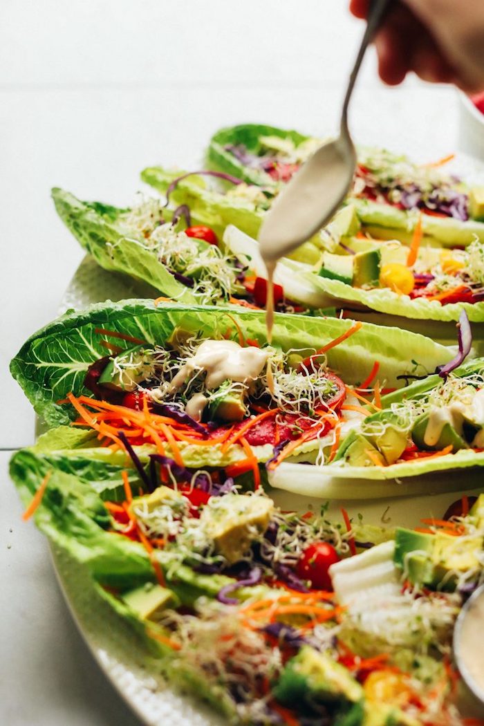 lettuce tacos, filled with vegetables, ground beef tacos, garlic sauce on top, white plate, marble countertop