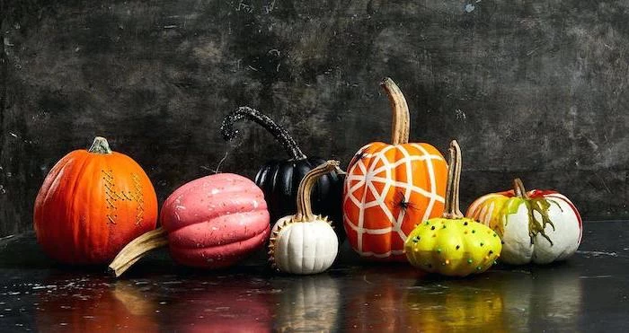 different shaped pumpkins, painted in different colors, easy pumpkin carving, black background, halloween pumpkin faces to carve