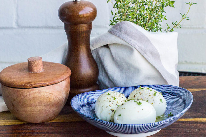 easy keto meals, three boiled eggs, with thyme and butter, in a blue and white bowl, wooden table