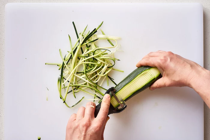 making zucchini noodles, with julienne peeler, white cutting board, how to make zoodles