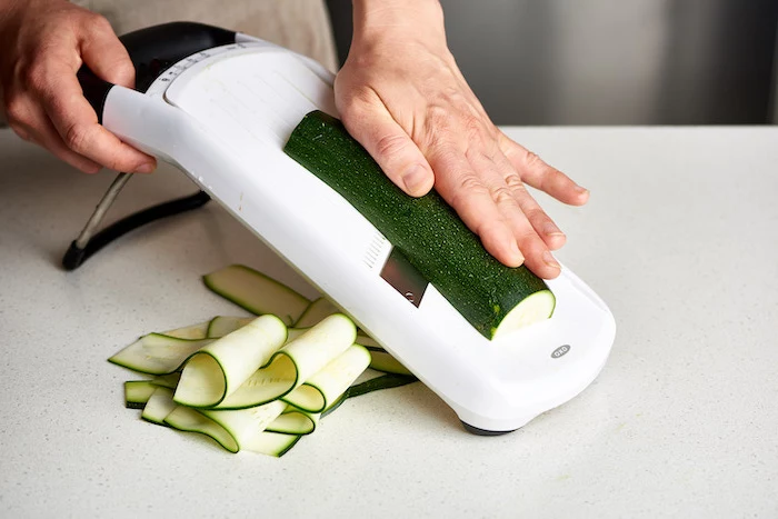 making zucchini noodles, with mandoline, how to make zoodles, white countertop, thin slices