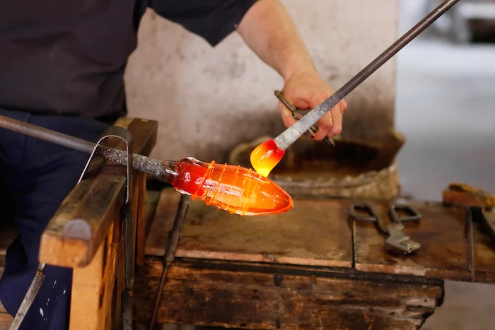 man holding tools, on wooden table, molten glass, murano glass chandelier, man with black shirt