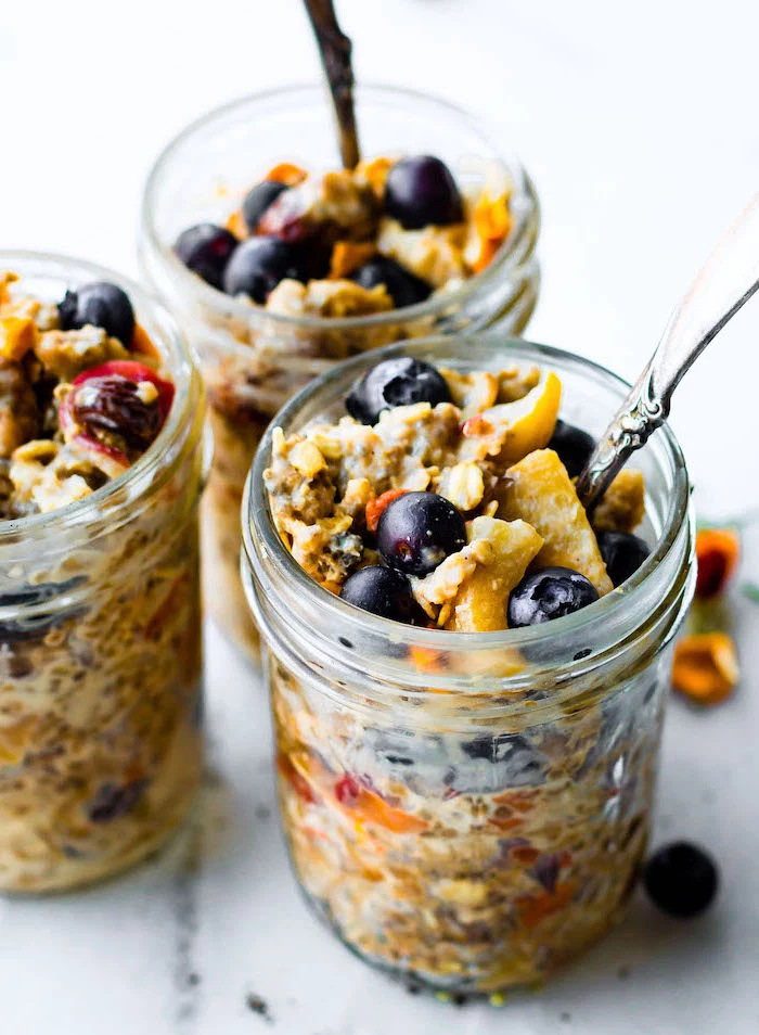 granola and yoghurt, berries inside a mason jar, with silver spoon, easy lunches for work, white wooden table
