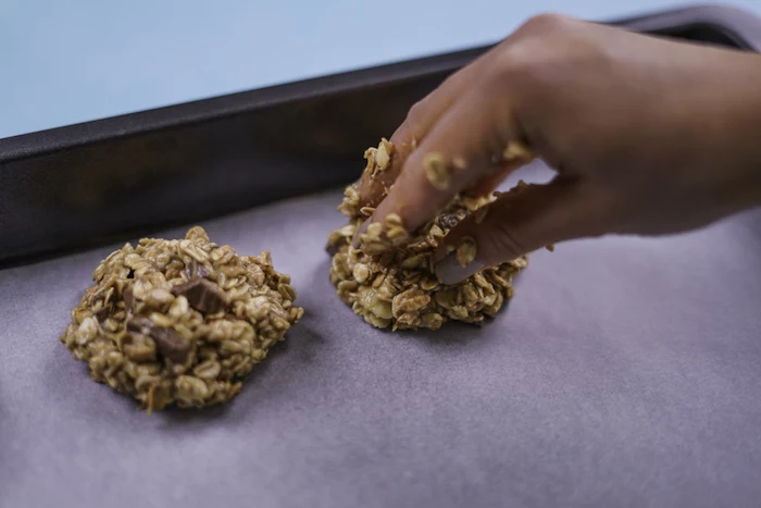 oatmeal cookies, tasty chocolate chip cookie, white baking paper, in a baking tray, blue table