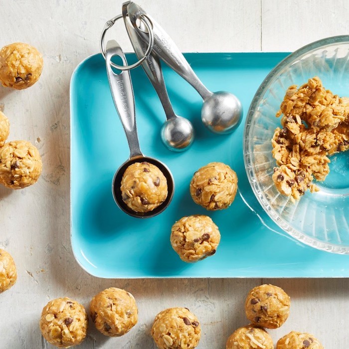 blue tray, measuring spoons, oatmeal mix, in a glass bowl, tasty chocolate chip cookie, wooden table