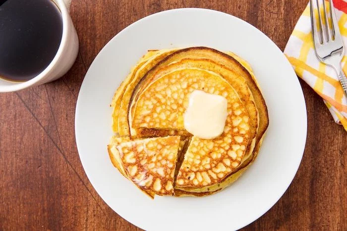 stack of pancakes, butter on top, on white plate, wooden table, coffee mug, high protein low carb breakfast