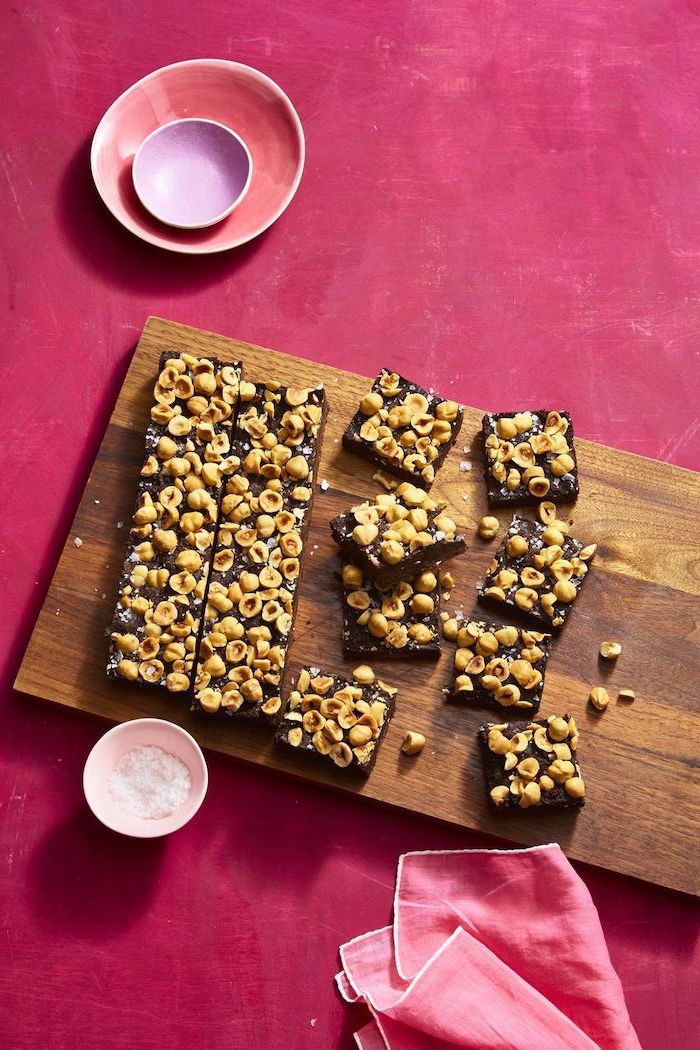 chocolate pecan bars, cut up, on a wooden cutting board, easy dessert recipes, pink table, pink table cloth