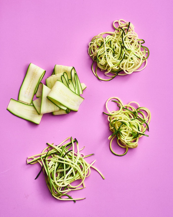 how to make zoodles, four different ways, zucchini noodles, pink background