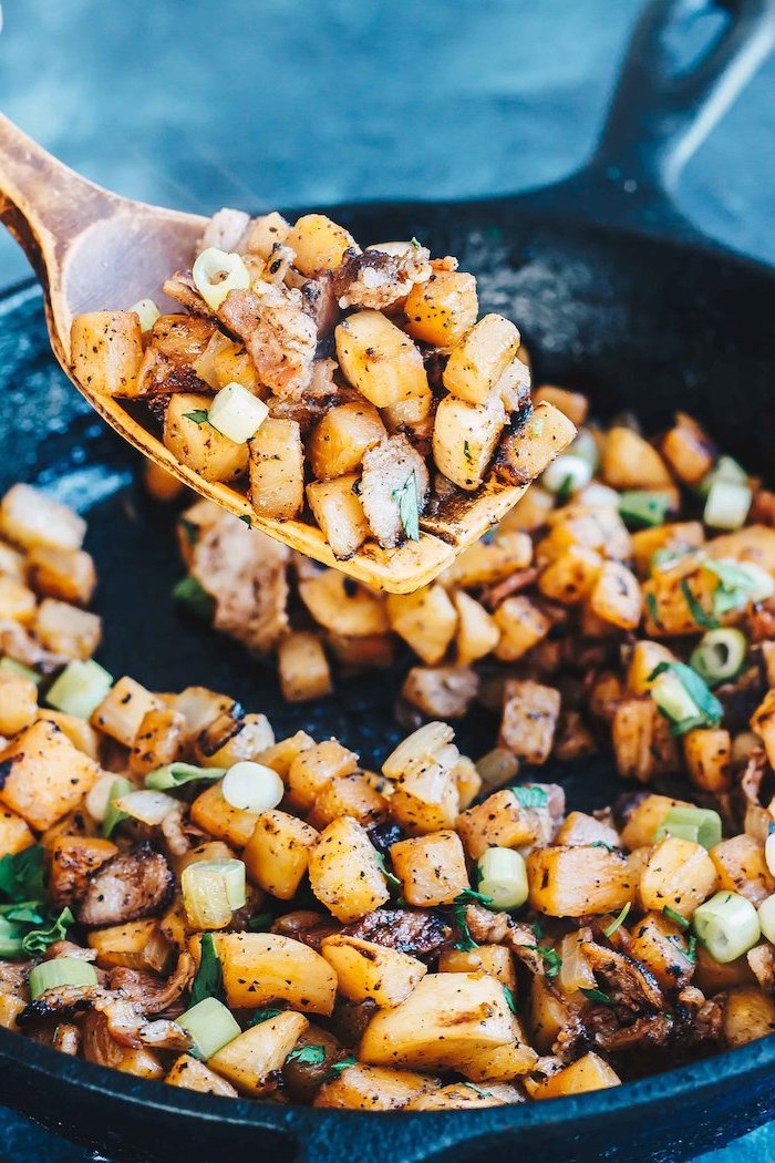 potatoes with bacon and onion, in a black frying pan, high protein low carb breakfast, wooden spatula