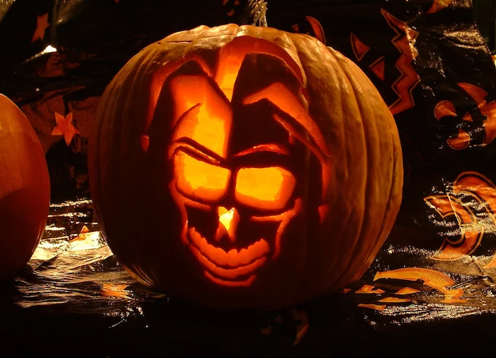 skull of a jester, carved into a pumpkin, lit by a candle, scary pumpkin carvings