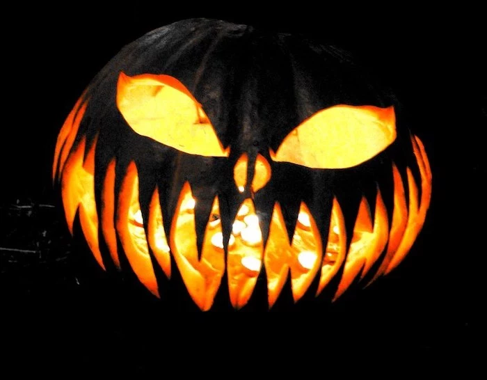 cool pumpkin carvings, large pumpkin, painted in black, lit by a candle, black background