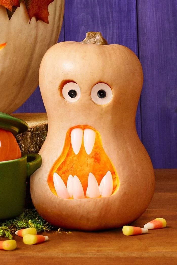 pumpkin with plastic eyes, with plastic teeth, cool pumpkin carvings, interesting shape, on a wooden table