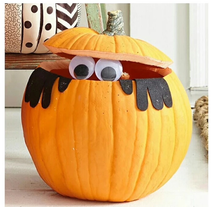 pumpkin with the top cut out, two plastic eyes, felt black arms, glued to it, unique pumpkin carving ideas